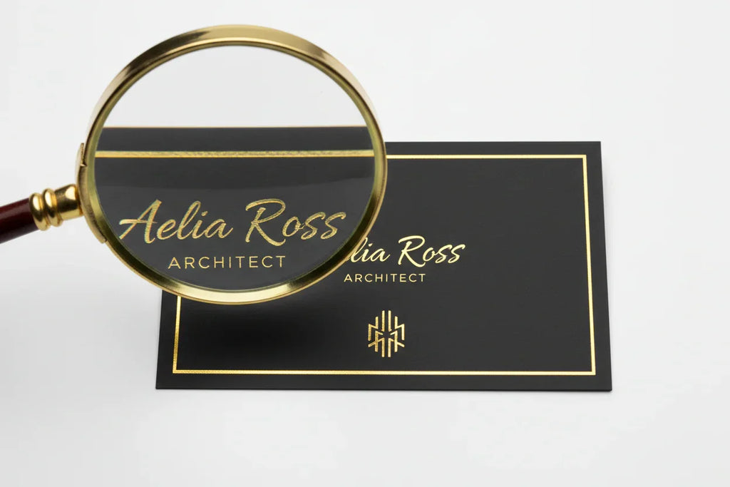 Black business card with raised metallic gold foil details and magnified design accent.