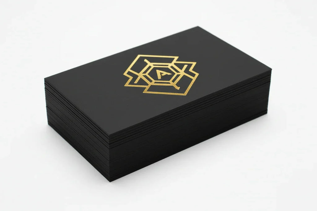Stack of black business cards with metallic gold foil geometric design on thick stock